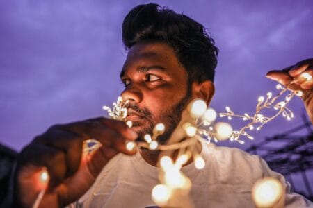 man in white shirt holding lighted sparkler